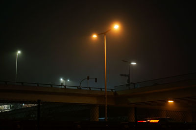 Low angle view of illuminated bridge against sky at night