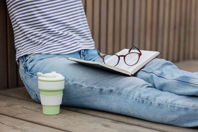 Eco friendly, a young and confident woman drinking coffee and reading a book