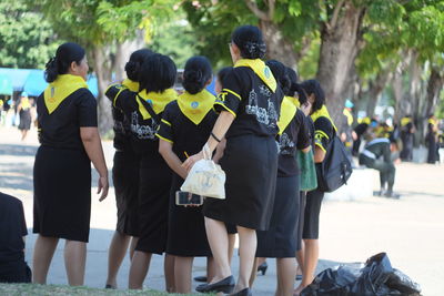 Rear view of women in uniform standing on road