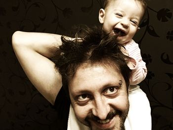 Portrait of father carrying happy baby on shoulders