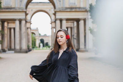 Young woman standing against wall in city