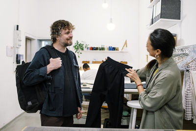 Female sales staff showing pants to male customer at workshop