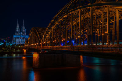 Illuminated bridge over river at night