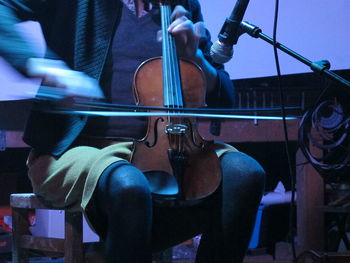 Midsection of man playing violin at home