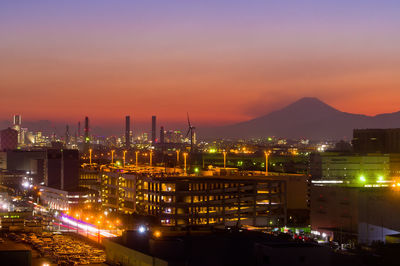 Illuminated buildings in city against sky at sunset