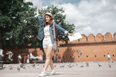 Full length of woman with arms raised against sky