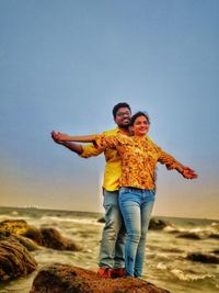 Full length portrait of happy friends standing on beach