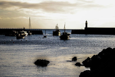 Silhouette sailboats in sea against sky