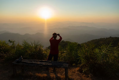 Rear view of man photo graphing during sunset