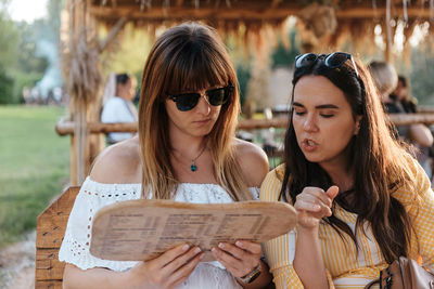 Two women looking at menu, ordering drinks in beach bar