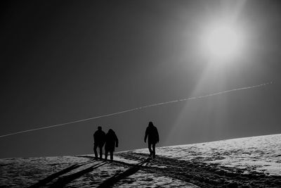 Silhouette men and woman against sky