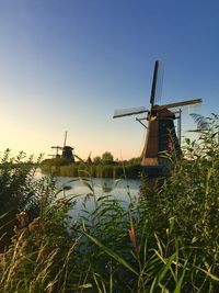 Traditional windmill on field against clear blue sky