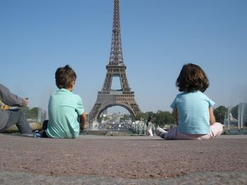 Rear view of men sitting against sky