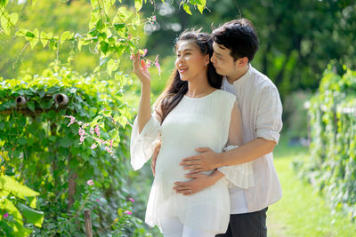 Young couple standing against plants