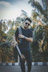 Man holding guitar in sunglasses