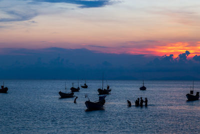 Silhouette sailboats in sea against sky during sunset