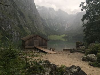 Wooden house amidst calm lake against mountain