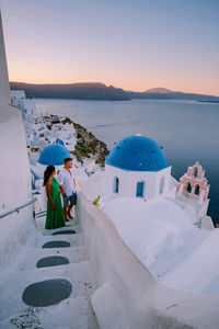 People by sea against sky during sunset