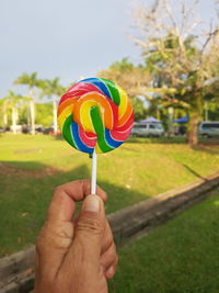 Close-up of hand holding multi colored lolipop 