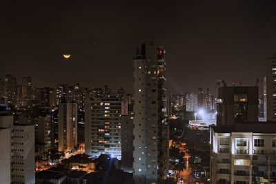 Illuminated buildings in city against sky at night