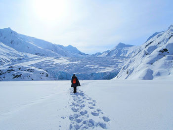 Rear view of woman on snowcapped mountain against sky