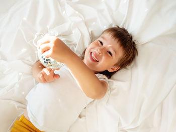 Little boy plays with sparkling mirror disco ball in bed and laughing happily. playful child.