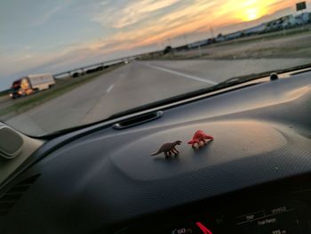 Close-up of car on road against sky during sunset