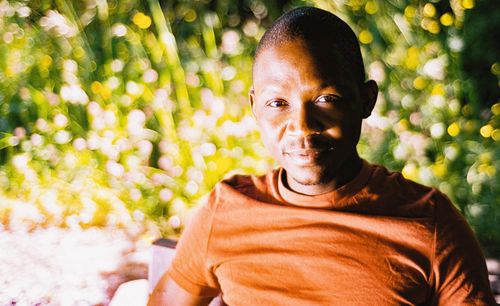 Portrait of young man from ghana sitting against plants