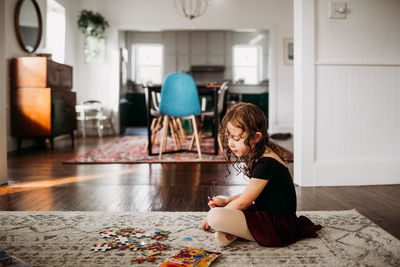 Young girl in ballet clothes sitting on floor doing puzzle