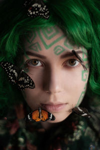 Close-up portrait of young woman with butterflies 