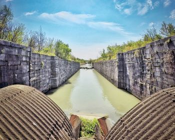 Scenic view of canal amidst wall during sunny day