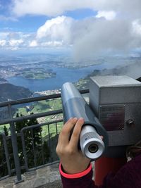 Close-up of man holding telescope against sky