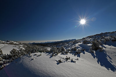 Scenic view of snow covered mountains against bright sky