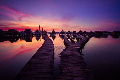 Jetty at calm lake against scenic sky