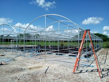 Incomplete metallic built structure on field against sky