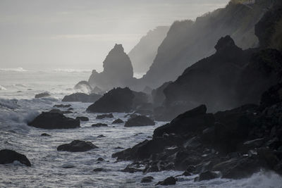 Rock formations on shore against sky