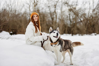 Portrait of woman with dogs on snow covered field