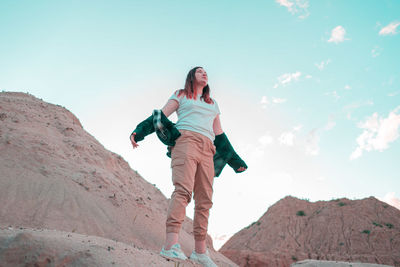 Low angle view of woman on rock against sky