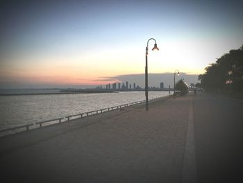 Road by sea against clear sky during sunset