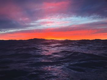 Scenic view of sea against dramatic sky during sunset