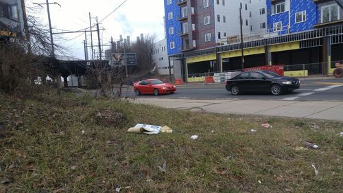 Cars on street by buildings in city against sky