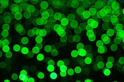 Defocused image of illuminated green lights at night