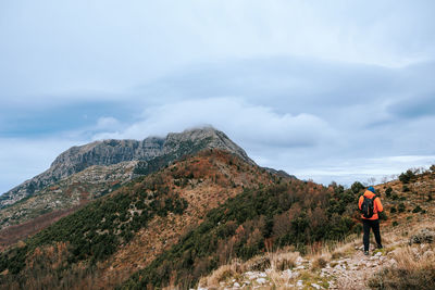 Rear view of man walking on mountain against sky