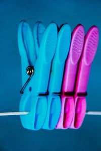 Close-up of clothespins on clothesline against blue background