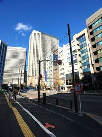 City street by modern buildings against sky