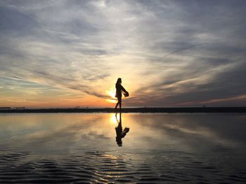 Silhouette man surfing on sea against sky during sunset