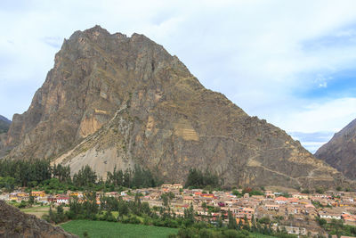 Scenic view of town by mountains against sky