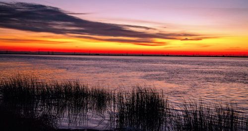 Scenic view of sea against dramatic sky during sunset