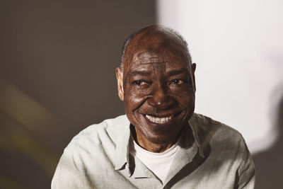 Smiling senior man looking away against white background