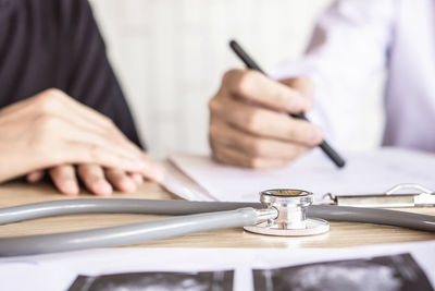 Close-up of doctor discussing medical report with patient in clinic